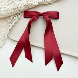 Detail view of a burgundy satin bow hair tie with long ribbons on a lace background