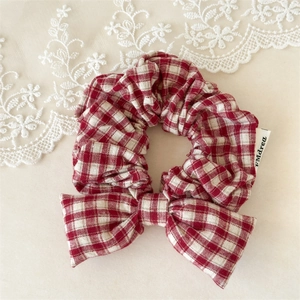 Detail showing red and white checkered bow hair scrunchie with woven cotton texture