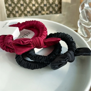 Close-up of red and black satin bow hair scrunchies with elegant pleated texture on a plate