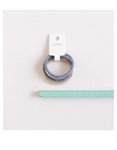 Dettaglio di tre elastici per capelli in blu, grigio e beige su un supporto di carta