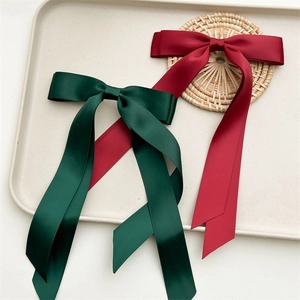 Detail of burgundy and dark green satin bow hair ties with long flowing ribbons