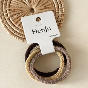 Set of four seamless elastic hair ties in brown and beige tones on a cream background