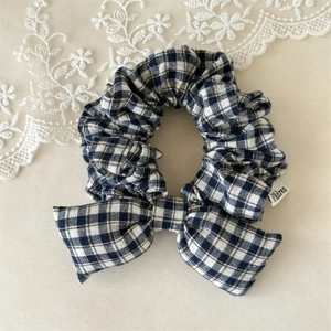 Detail of blue plaid bow scrunchie with soft cotton filling and woven side label