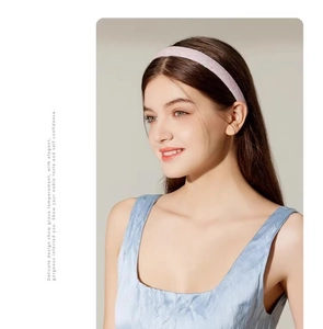Close-up of light pink glitter headband worn by a model against a clean grey background