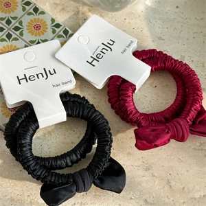 Detailed view of satin bow scrunchies in elegant black and burgundy red with silk texture