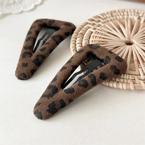 Close-up of leopard print plush hair clips on a woven coaster with a minimalist background