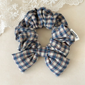 Close-up of red and blue plaid cotton bow scrunchie with detailed fabric texture