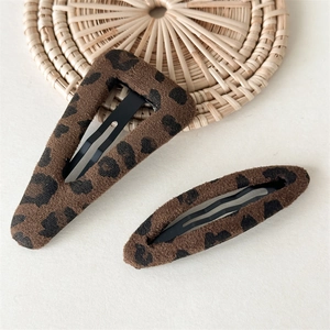 Detail view of two plush leopard print hair clips with vintage brown flocking texture