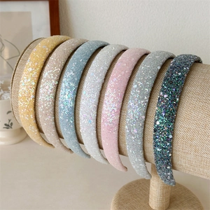 Detail showing seven colors of sparkling wide headbands with sequins on a display stand