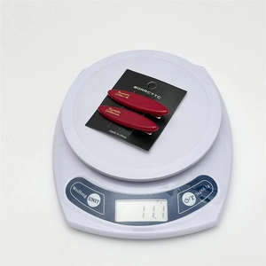 Detailed view of red acetate hair clips on a scale weighing 11.1g for weight reference