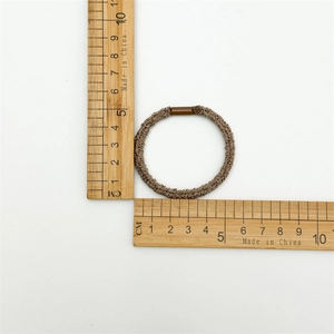 Detail shot showing a brown elastic seamless hair tie measured with a ruler at 5.2cm
