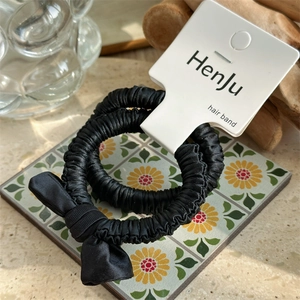Close-up of black satin scrunchie set with bow detail on a stylish display card