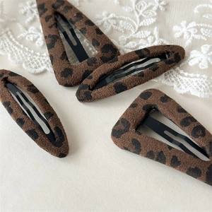 Close-up of leopard print plush hair clips in triangle and oval shapes with soft texture