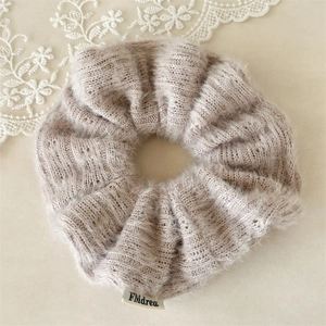 Détail macro du chouchou en tricot beige pelucheux avec texture côtelée et étiquette