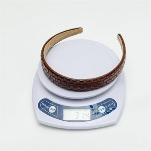 Detail of dark brown lattice leather headband on a scale showing 31.4g lightweight design