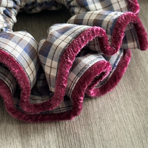 Retro plaid fabric scrunchie with burgundy velvet trim on a rustic wood background