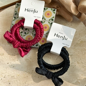 Detail of red and black satin bow hair ties displayed on a branded display card