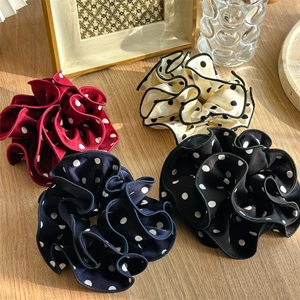 Set of four polka dot hair scrunchies in red, cream, navy, and black on a wooden desk