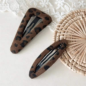 Close-up of plush leopard print hair clips with soft fabric texture and warm autumn feel