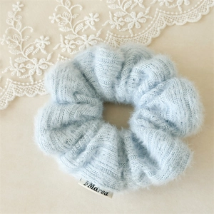 Détail d'un chouchou en tricot peluche bleu avec étiquette de marque et texture douce