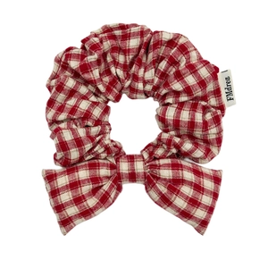 Red plaid checkered hair scrunchie with bow tie and fabric label on white background