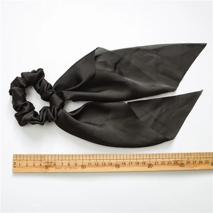 Detail of high-elastic black ponytail scrunchie with long ribbon streamers and ruler