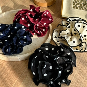 Close-up of vintage large polka dot scrunchies in four colors on a wooden table