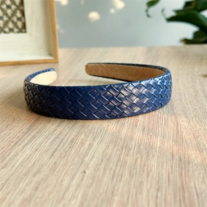 Macro detail of dark blue braided leather headband with classic cross texture design
