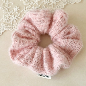 Détail d'un chouchou en peluche rose avec texture mohair douce et étiquette logo