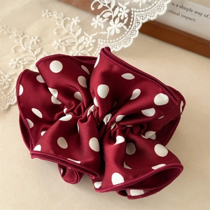 Détail d'un chouchou en satin bordeaux à pois blancs avec des couches de froufrous
