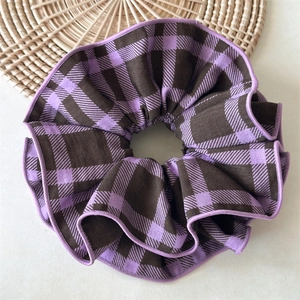 Macro detail of purple plaid fabric scrunchie showing twill texture and pleated design