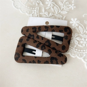 Detail of two plush leopard print BB hair clips on a white card with lace decoration