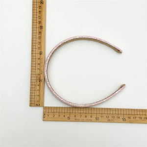 Top view of pink sequin headband on a white background with a ruler for size reference