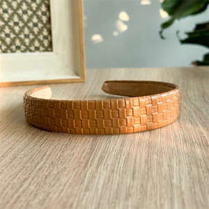 Detailed close-up of brown textured leather plaid headband on a wooden table