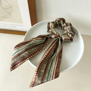 Detail of vintage geometric silk-like scrunchie and hair scarf on a white ceramic plate