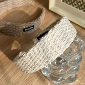 Close-up of knit headbands showing coarse texture and hand-stitched decorative tags