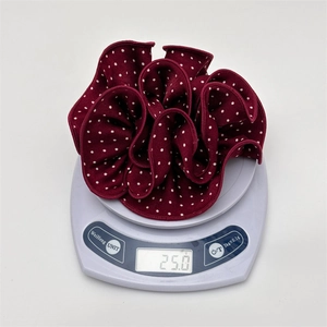Detailed view of large burgundy polka dot scrunchie weighing 25 grams on a scale
