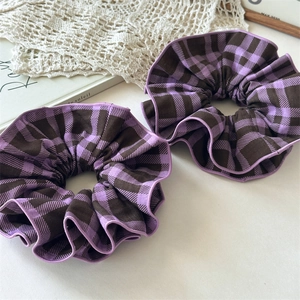 Detail of two-piece plaid fabric hair scrunchies in purple and brown with a soft texture