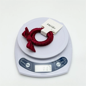 Elegant burgundy silk bow hair scrunchie shown on a white digital scale weighing 11.7 grams