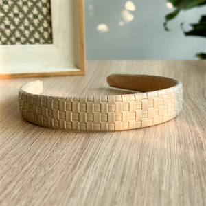 Close-up of beige woven leather headband showing detailed basket weave texture on wood