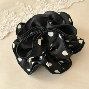 Détail du chouchou en satin noir à pois avec des bords à volants multicouches stylés