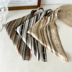Three bohemian striped triangle hair scarves with elastic bands on a rustic table