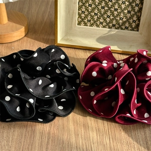 Close-up of black and burgundy polka dot scrunchies with elegant pleated silk texture