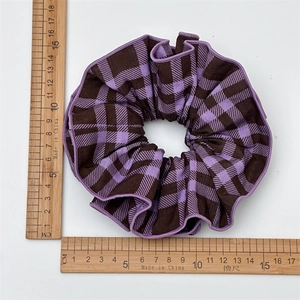 Detailed view of a purple plaid scrunchie with a diameter of about 12cm on a ruler