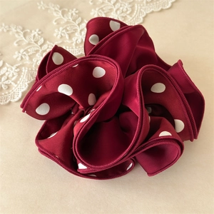 Vue détaillée du chouchou en satin bordeaux à pois avec plis multicouches et bords cousus