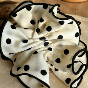 Close-up of cream vintage polka dot scrunchie with black piping and pleated texture