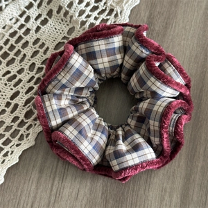 Detailed view of the checkered fabric hair scrunchie with burgundy velvet edge trim