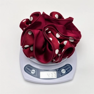 Mesure du poids d'un chouchou en satin bordeaux à pois sur une balance électronique