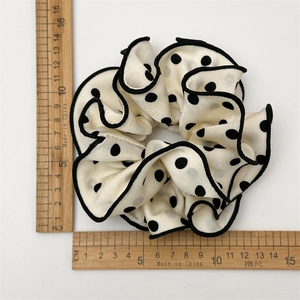 Retro cream scrunchie with black polka dots and wavy edge, measured at 12cm diameter