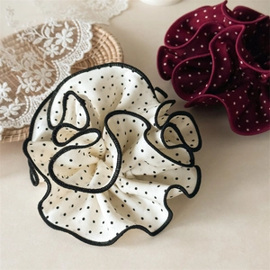 Detailed view of polka dot chiffon scrunchies in white and burgundy on a tray